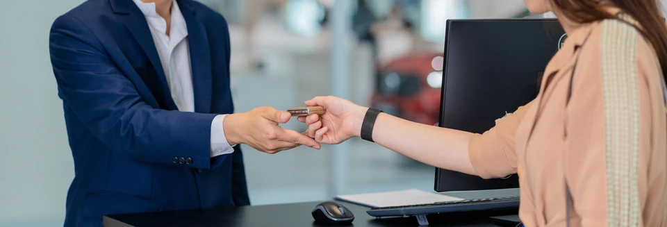 Scène d'intérieur professionnel avec deux personnes effectuant une remise de clés automobile