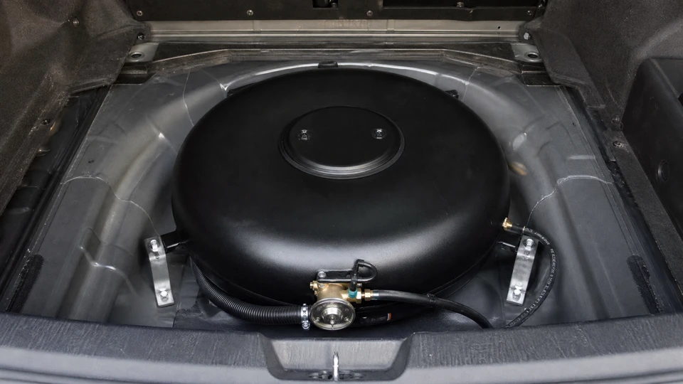 Mécanicien automobile inspecte un moteur sous le capot ouvert d'un véhicule, tenant un carnet de maintenance avec grille de données et stylo pour noter les vérifications techniques
