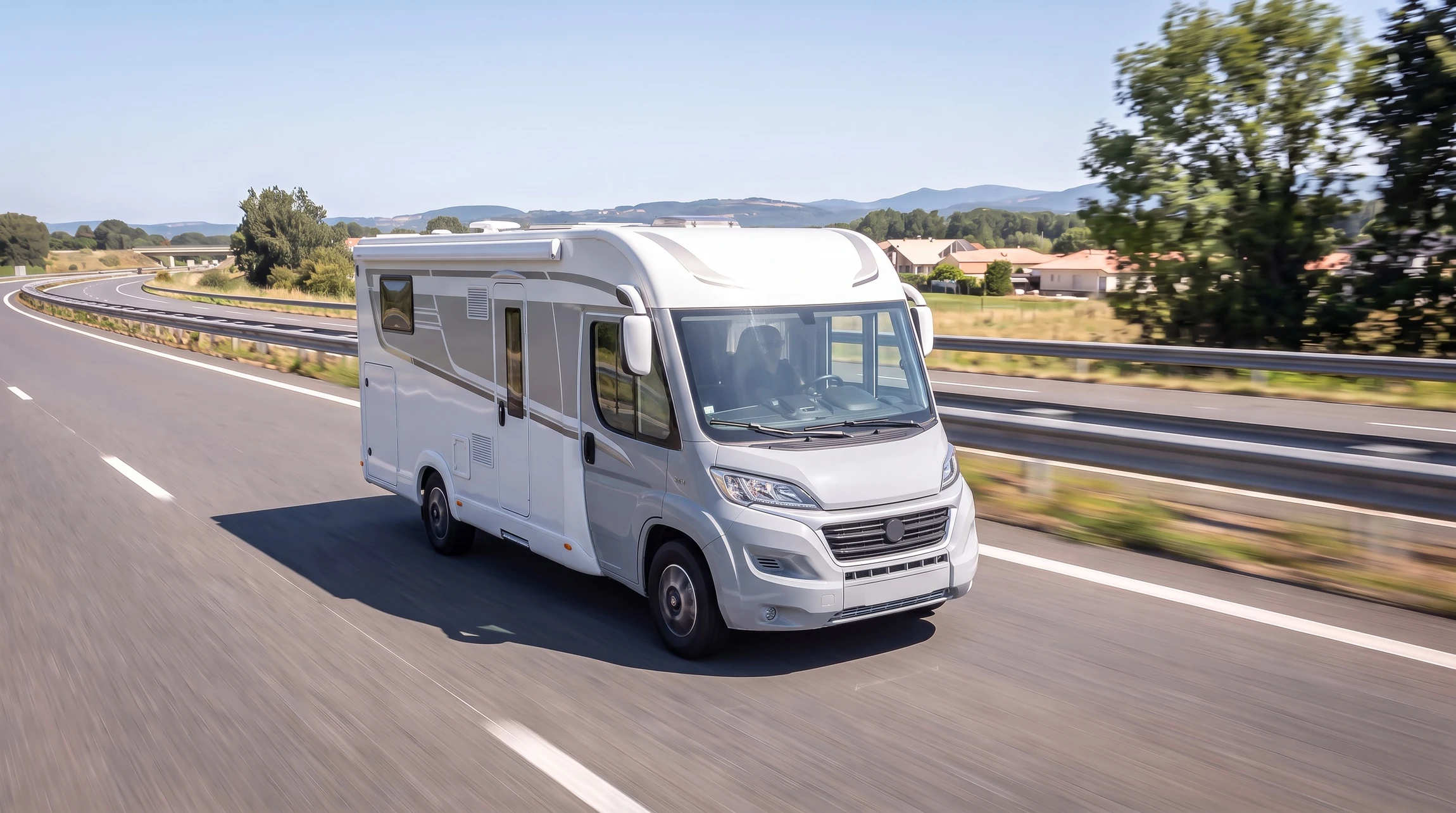 Camping-car blanc stationné sur route goudronnée dans paysage montagneux